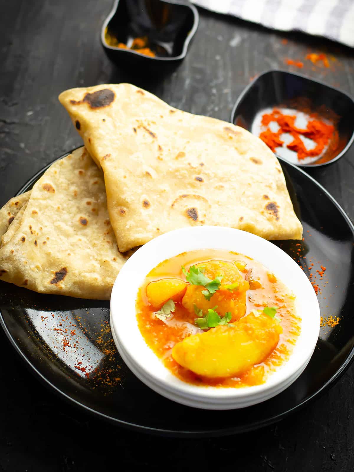 potato curry served with Indian flatbread over the dinner table