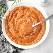 Roasted veggie sauce with tomato and garlic in a white bowl with a spoon.