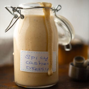 Creamy Spicy Cashew Dressing in a bowl, garnished with fresh cashew nuts.