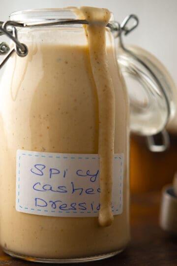 Creamy Spicy Cashew Dressing in a bowl, garnished with fresh cashew nuts.