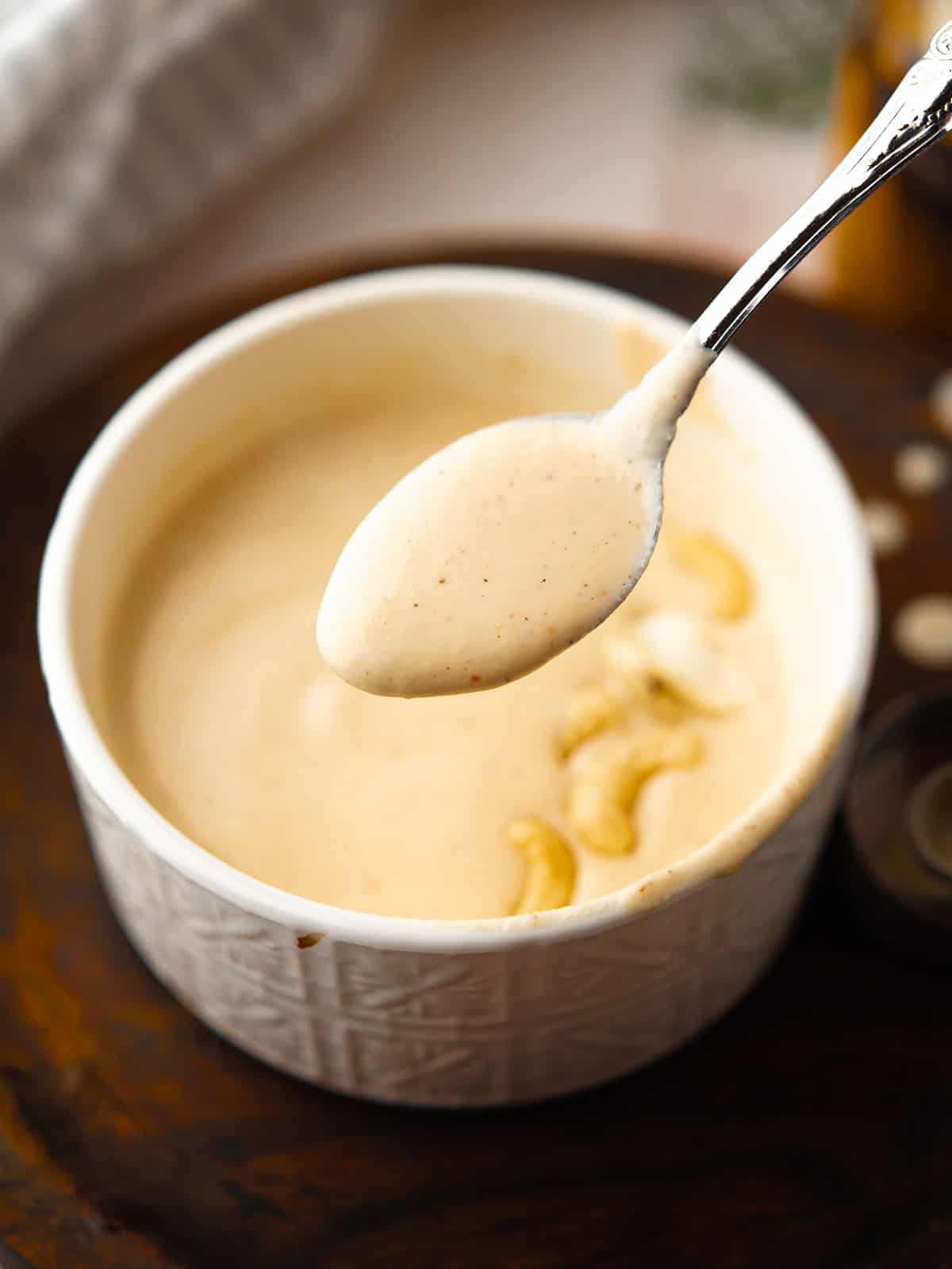 Close-up of Spicy Cashew Dressing in a spoon ready to drizzled over a salad.