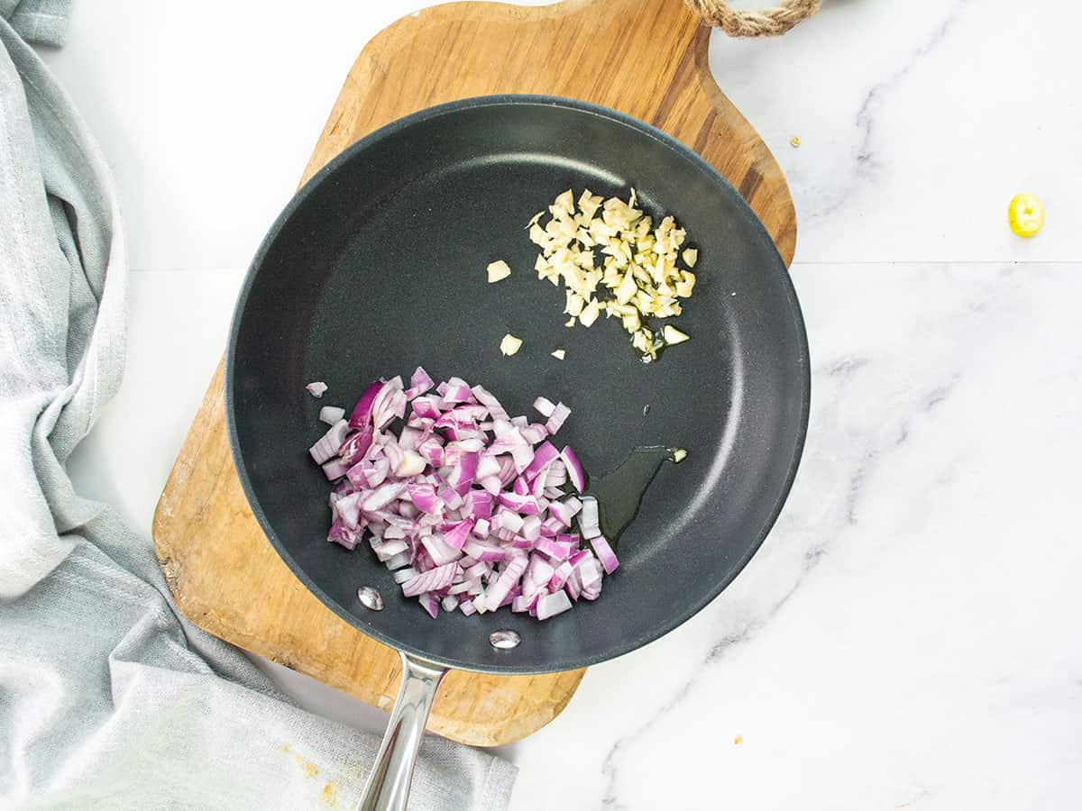 Cooking chopped onions and garlic in olive oil in a pan.