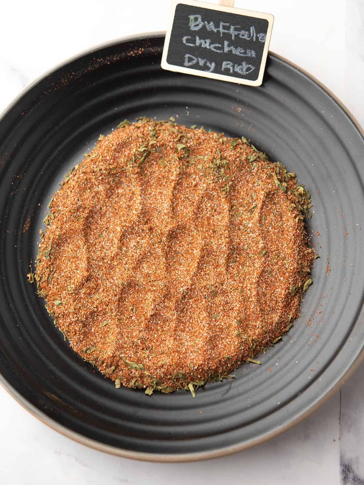 Bowl of Buffalo chicken wings coated in dry rub seasoning.