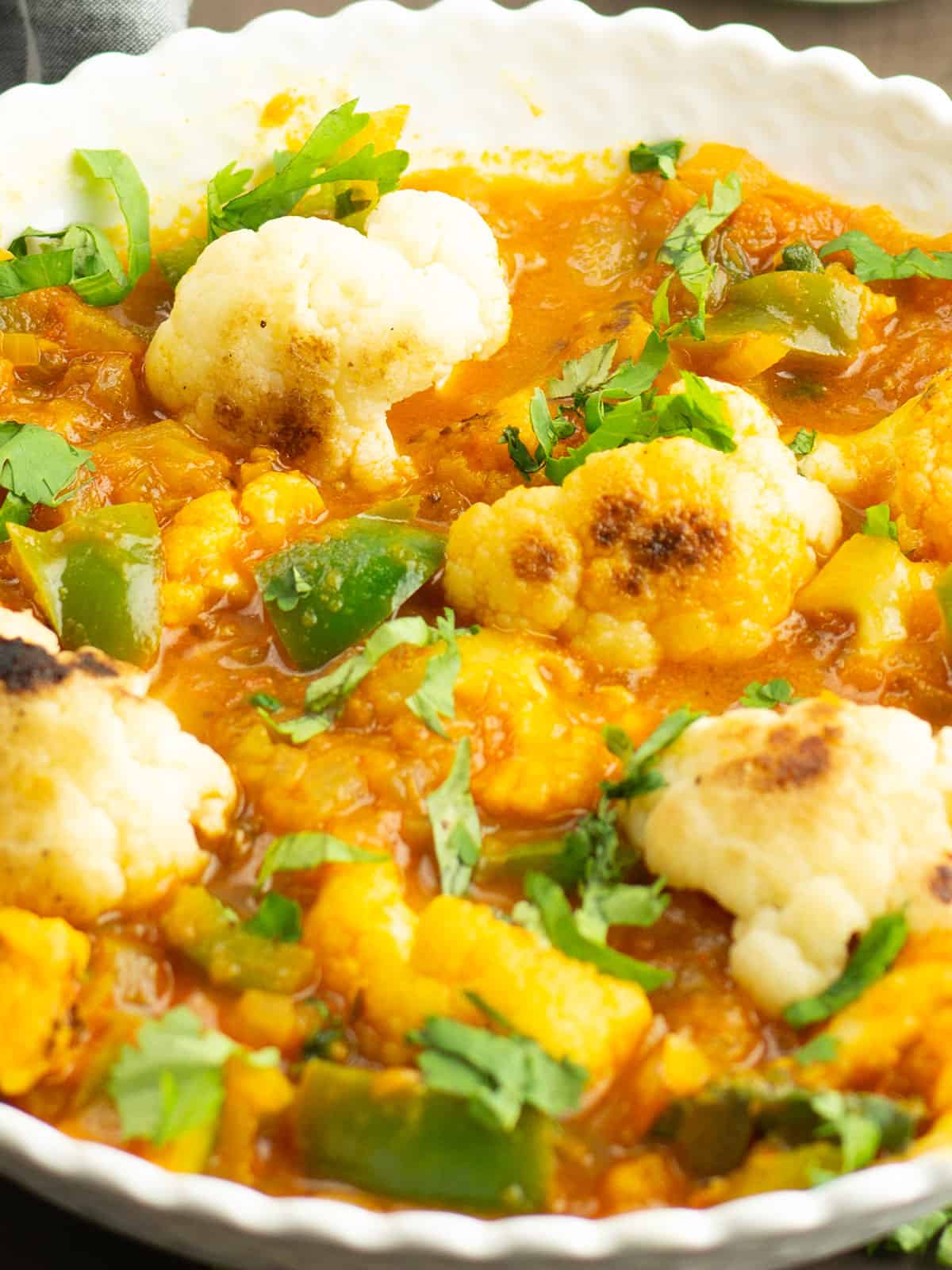 cauliflower curry garnished with cilantro served in a bowl
