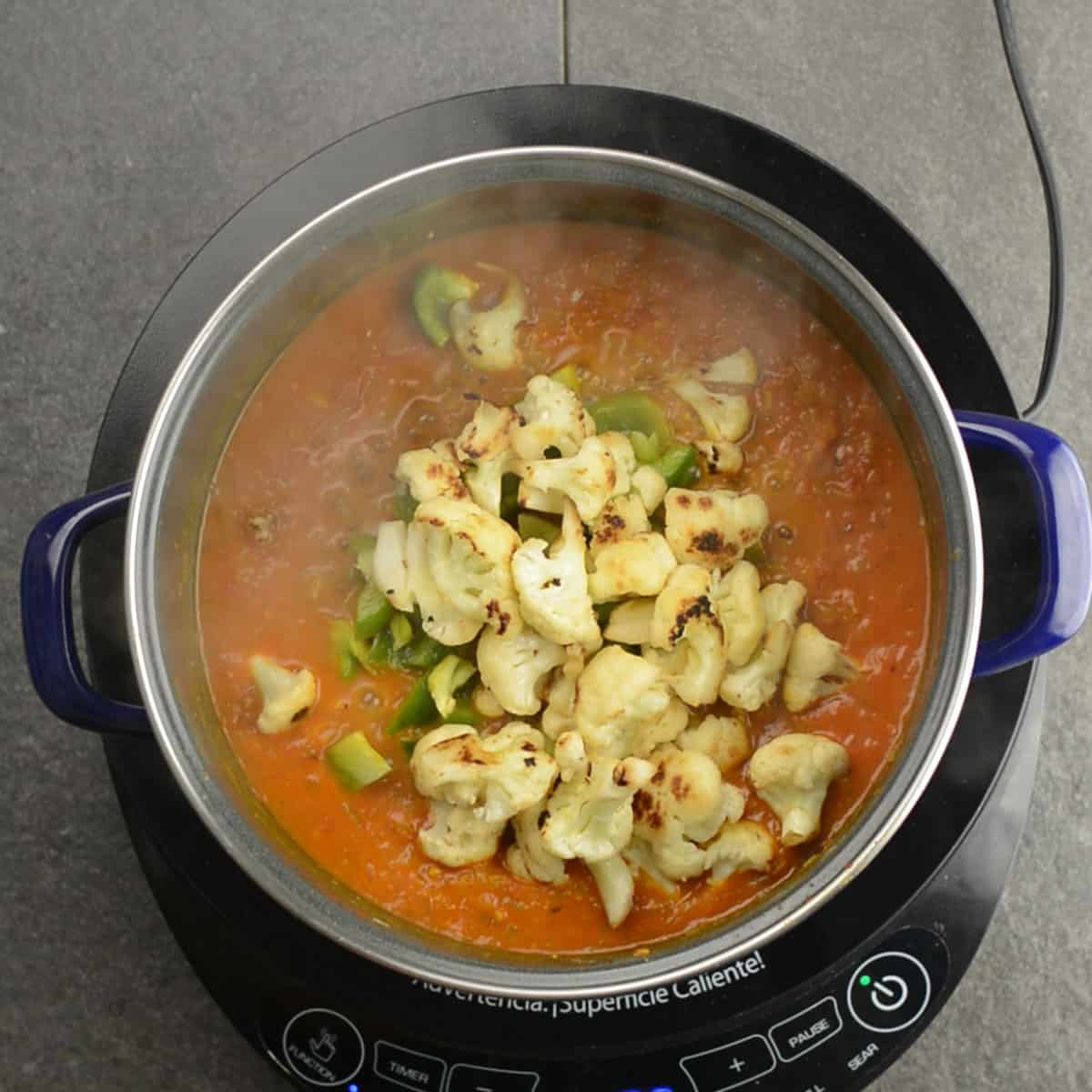adding the veggies to make the cauliflower curry