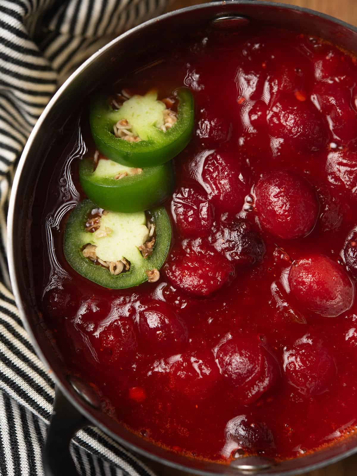 A bowl of cranberry jalapeño sauce with a vibrant red color and glossy texture.