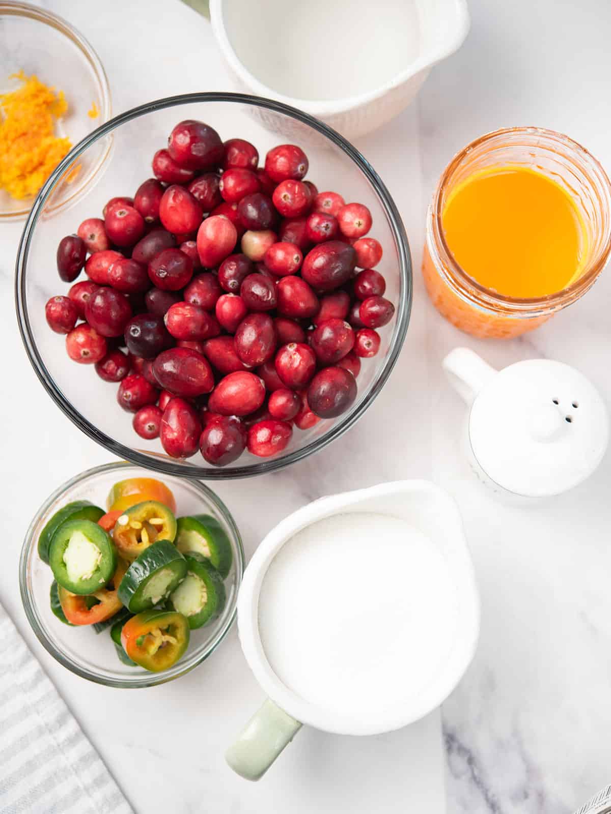 Fresh cranberries, jalapeños, sugar, and other ingredients arranged on a table for the sauce.