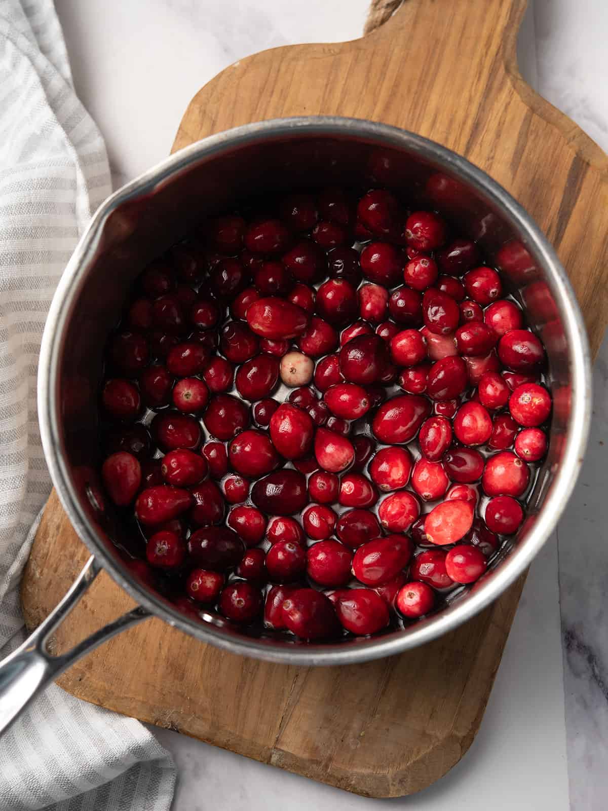 Cranberry jalapeño sauce simmering in a pot with bubbling texture.