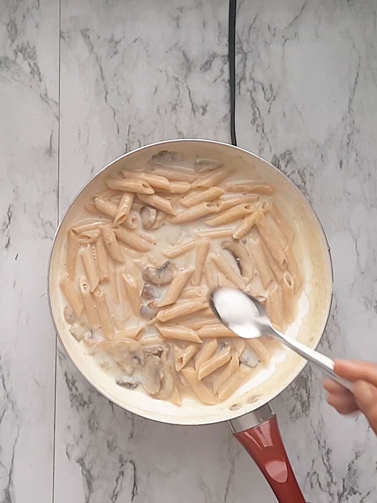 adding salt to the cream of mushroom pasta sauce.