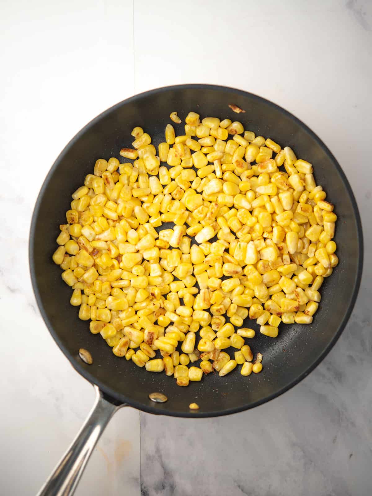 Sautéing corn in a skillet.