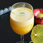 mango milkshake served in a tall glass with mint leaves as garnish