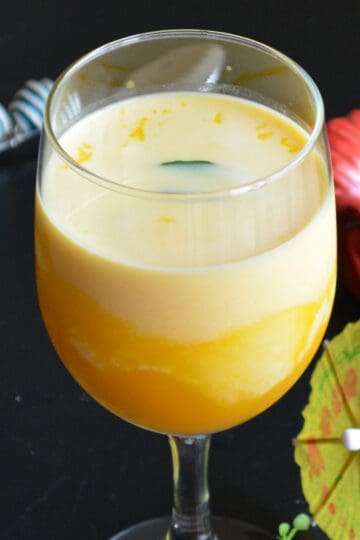 mango milkshake served in a tall glass with mint leaves as garnish