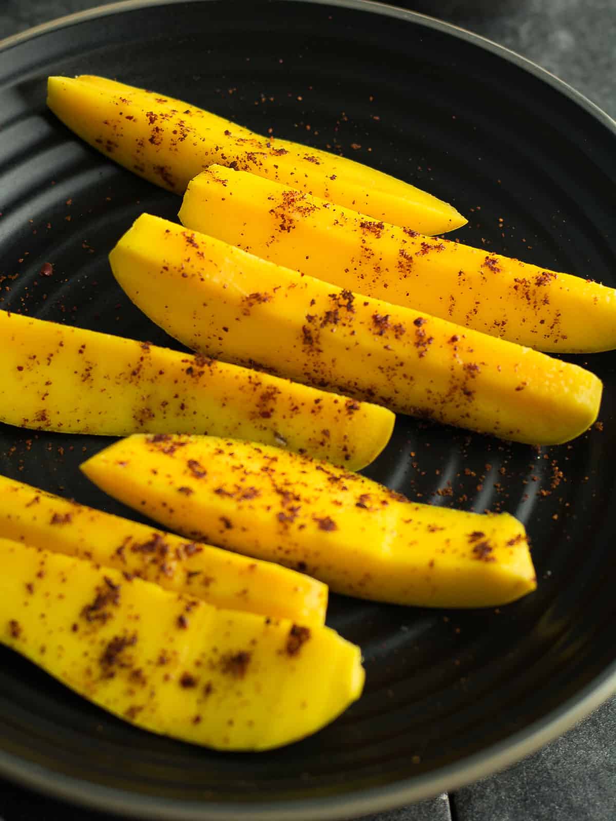 the close up view of the mango slices sprinkled with chili powder