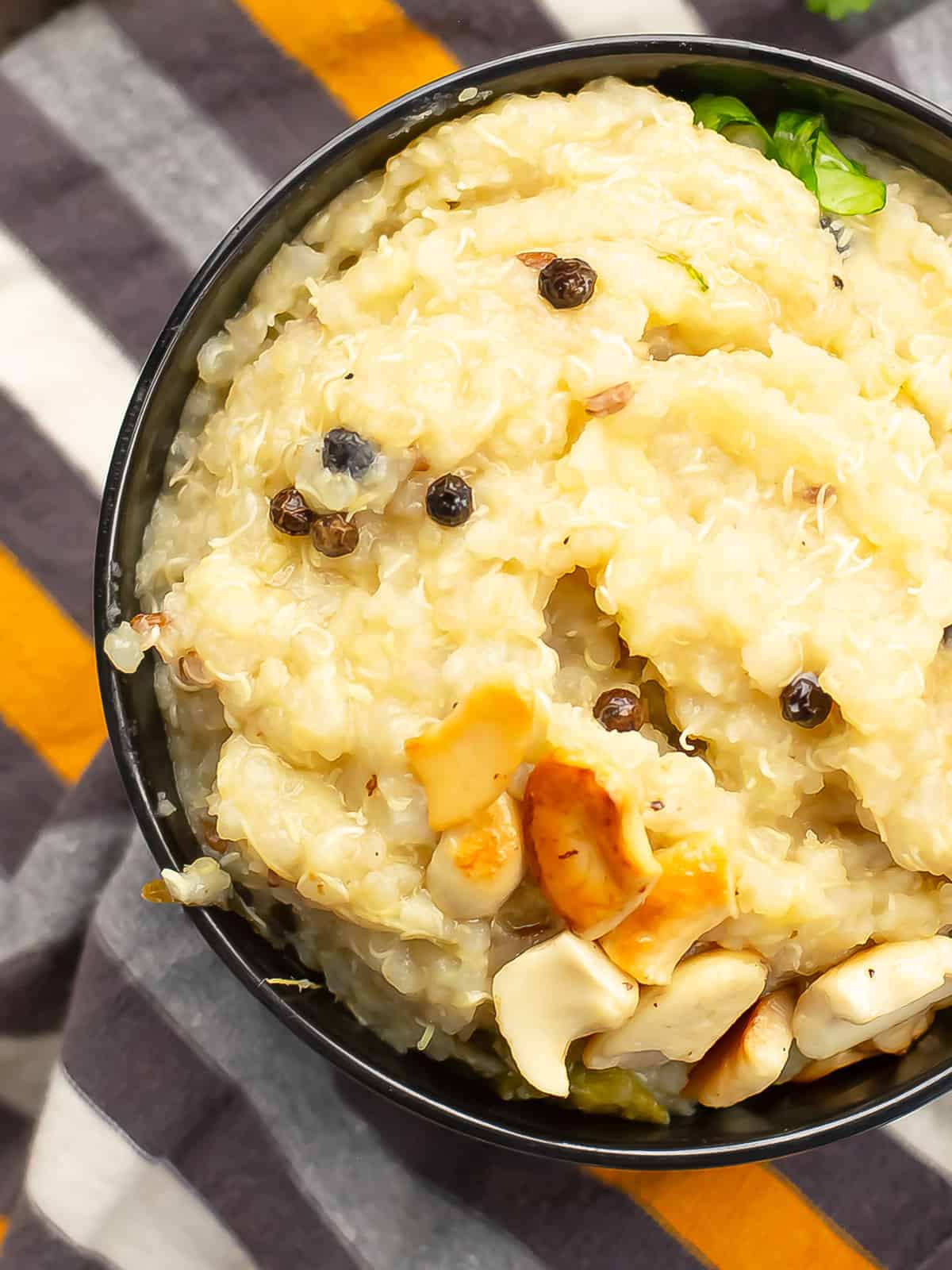 close view of quinoa pongal garnished with black pepper and cashews