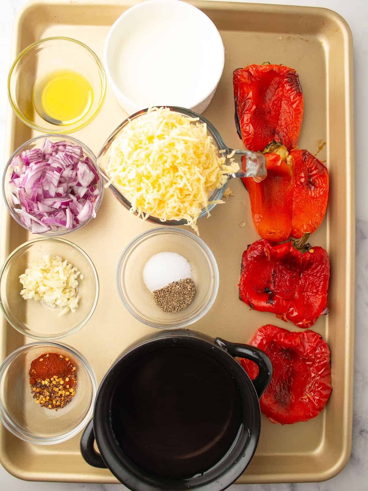 Ingredients for roasted red pepper gouda soup, including red peppers, onion, garlic, and cheese.