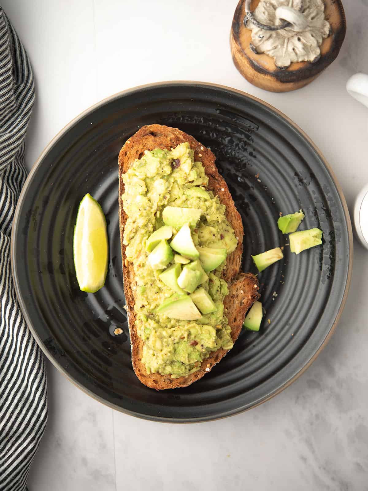 Spreading avocado mixture generously on crisp toasted bread.