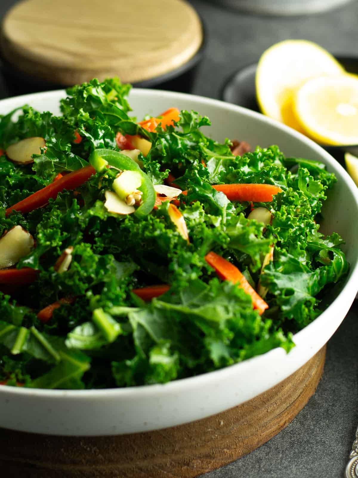 Close-up of spicy kale salad served in a white bowl with fresh ingredients and seasoning.