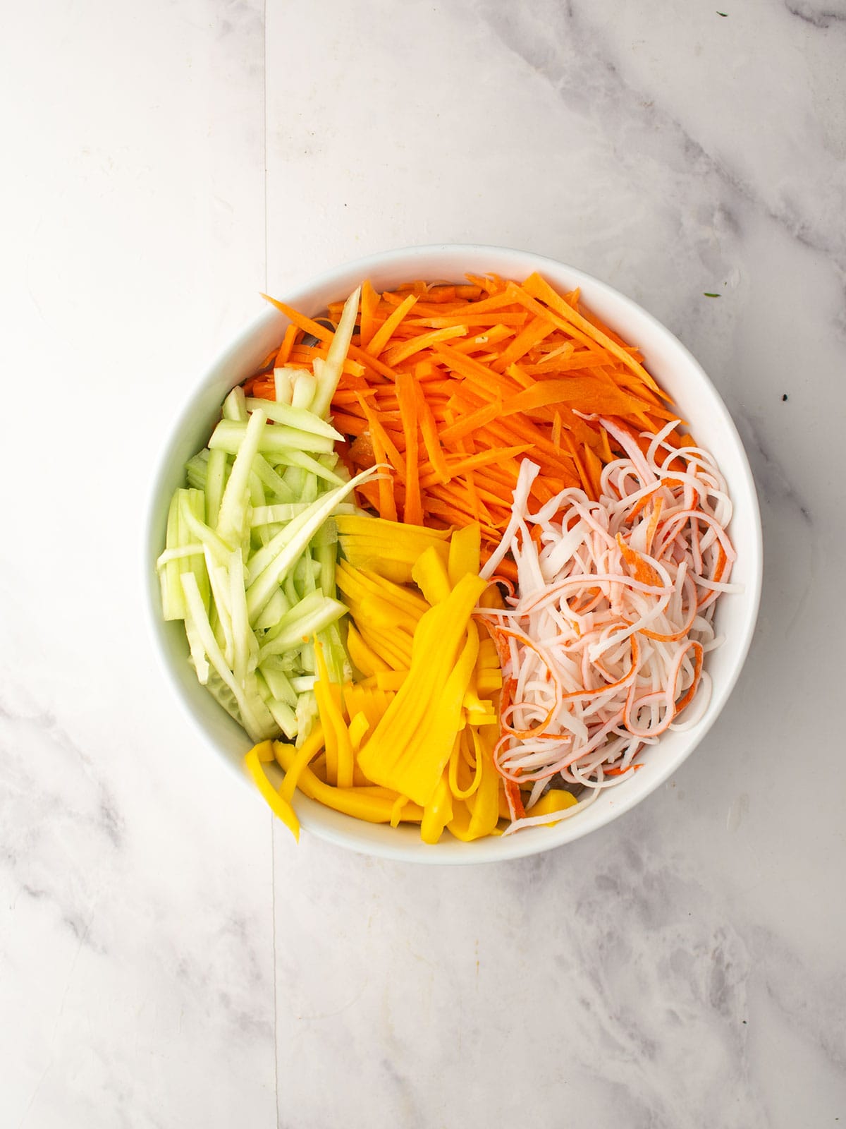 Julienned cucumber and carrots prepared for Spicy Kani Salad.