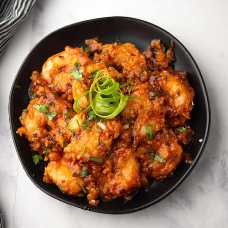 volcano shrimp served in sweet & spicy sauce in a plate garnished with green onion.