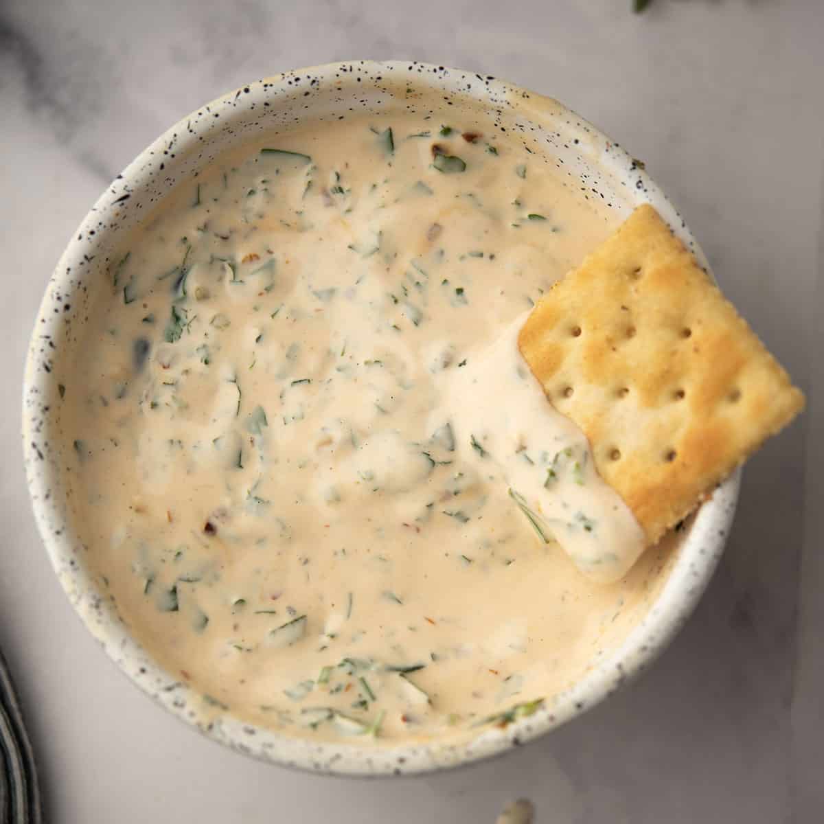 chimichurri aioli served in a bowl and dipped with cracker