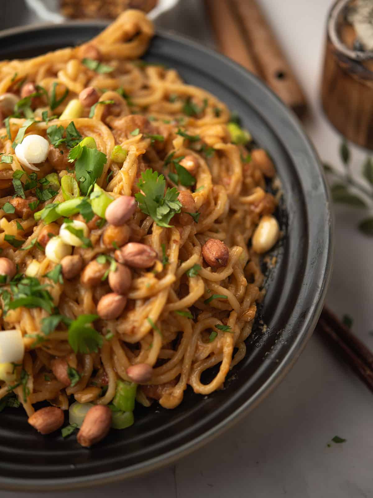 chili peanut noodles garnished with roasted peanuts and chopped cilantro.