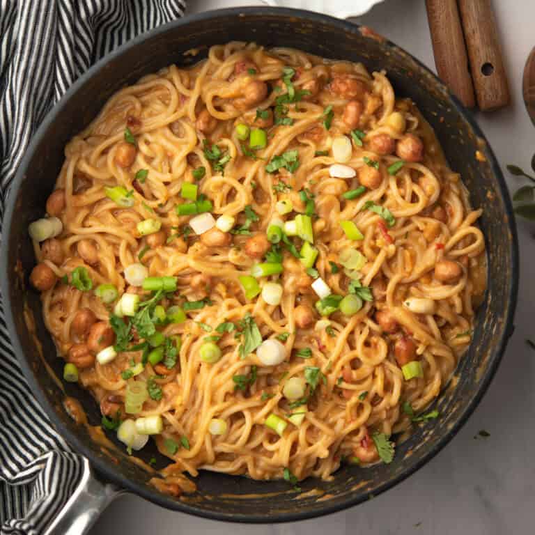 creamy, spicy chili peanut noodles served in a pan garnished with green onion and cilantro.