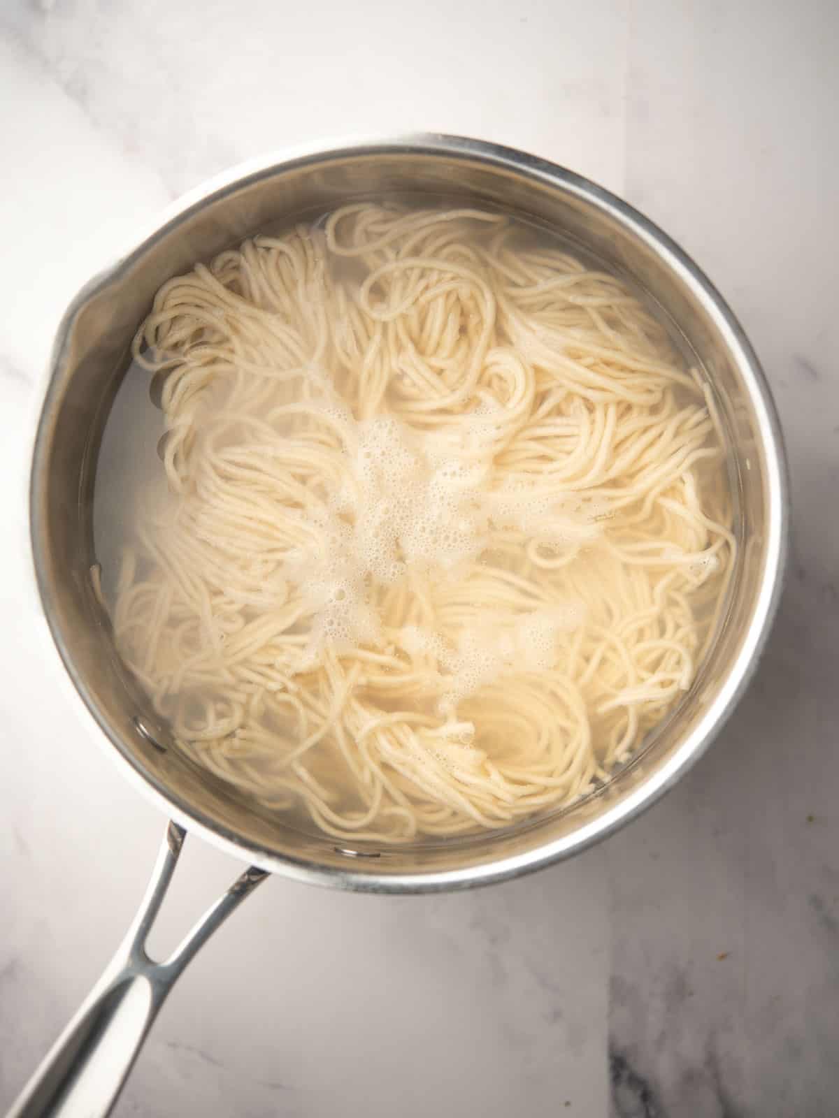 Cooking noodles in boiling water for Chili Peanut Noodles dish.