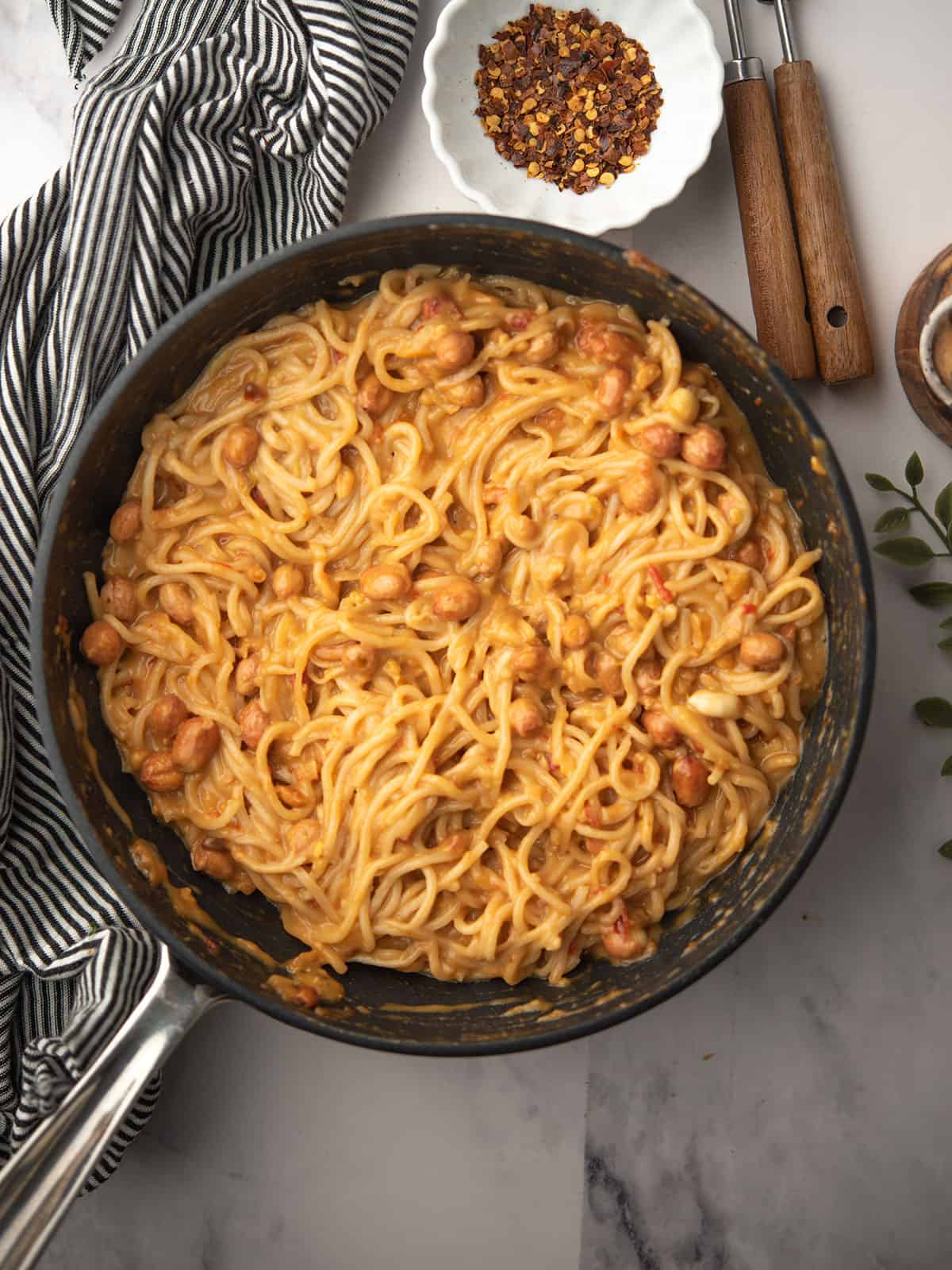 adding the noodles in the chili oil peanut sauce