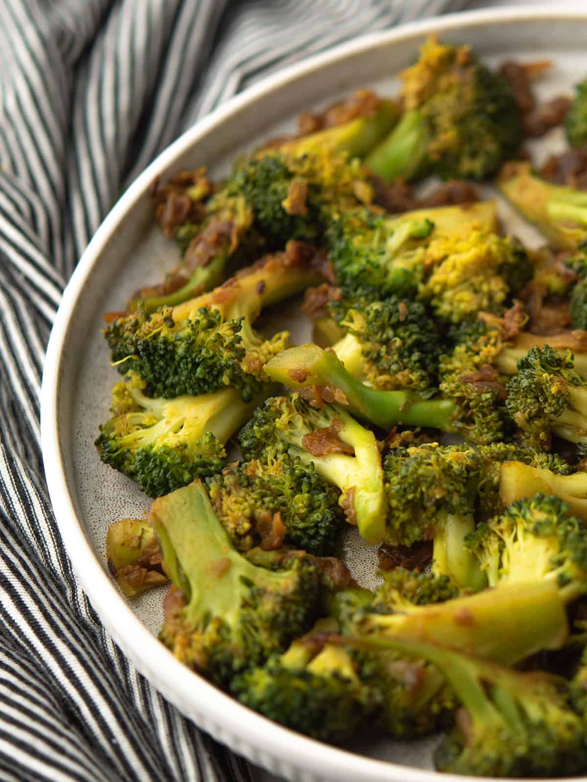 Close-up of flavorful curried broccoli garnished with lemon juice.