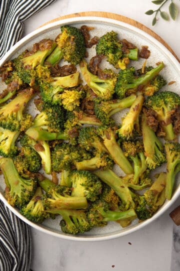 the tender curried broccoli tossed into spice blend and onion in a plate as a side dish for the dinner
