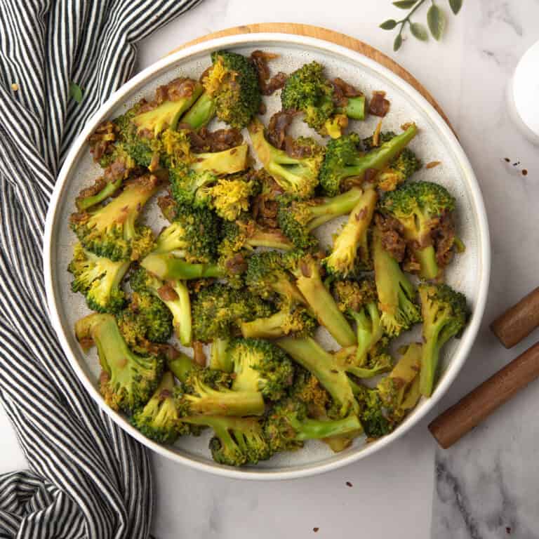 the tender curried broccoli tossed into spice blend and onion in a plate as a side dish for the dinner