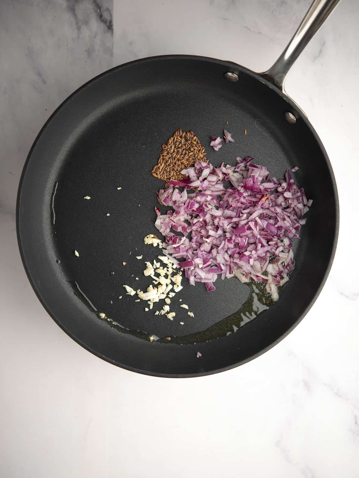Sautéing chopped onions and minced garlic in a pan.