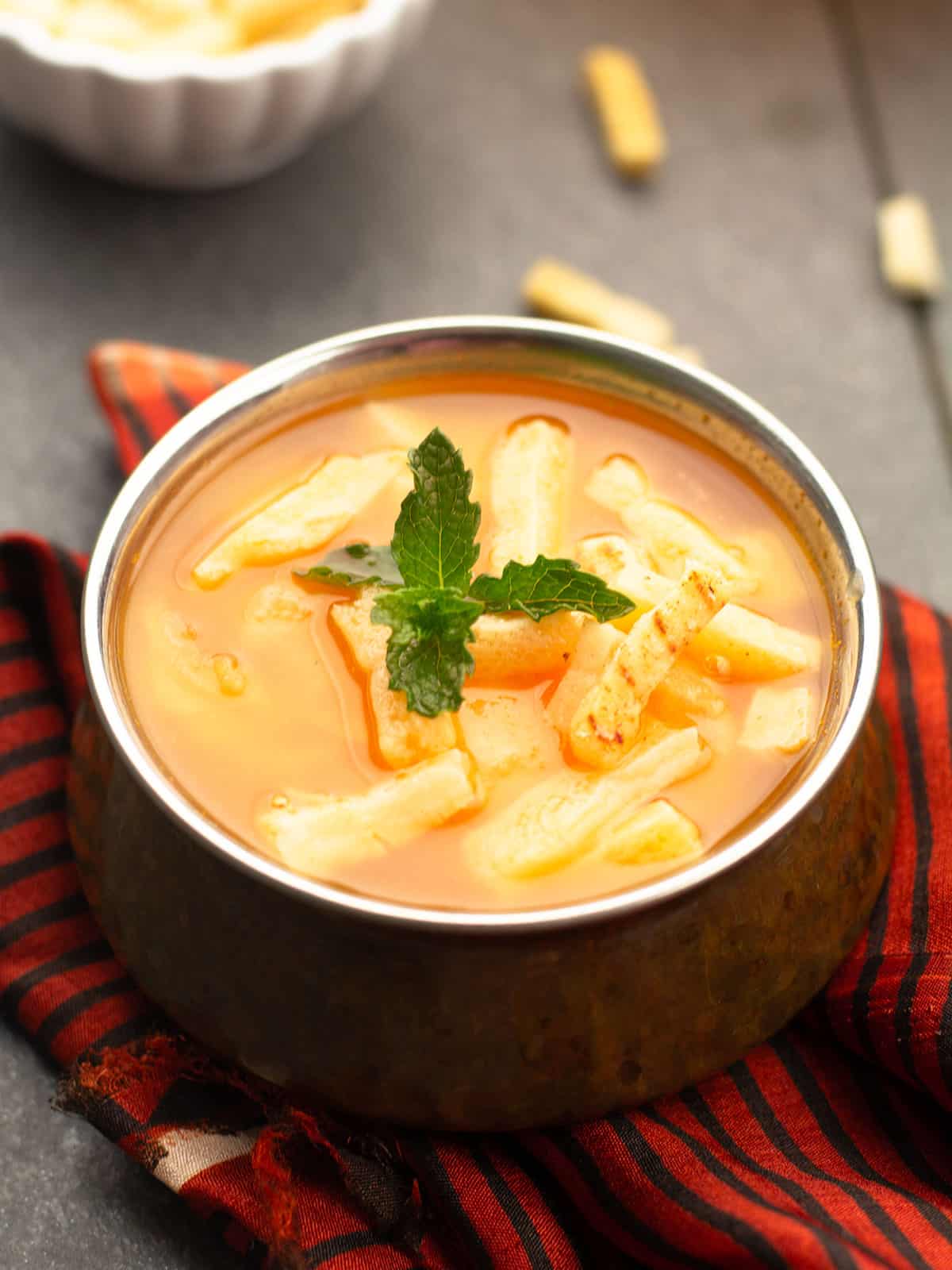clear tomato soup garnished with mint leaves is ready to serve