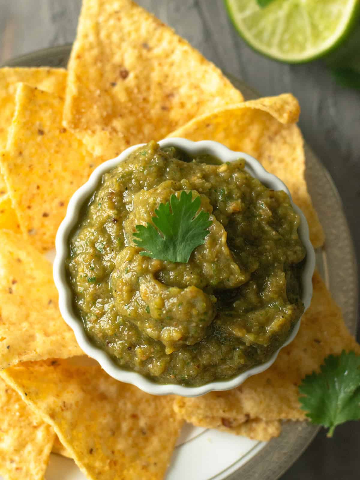 roasted green tomato salsa in a bowl served with tortilla chips and lime wedges
