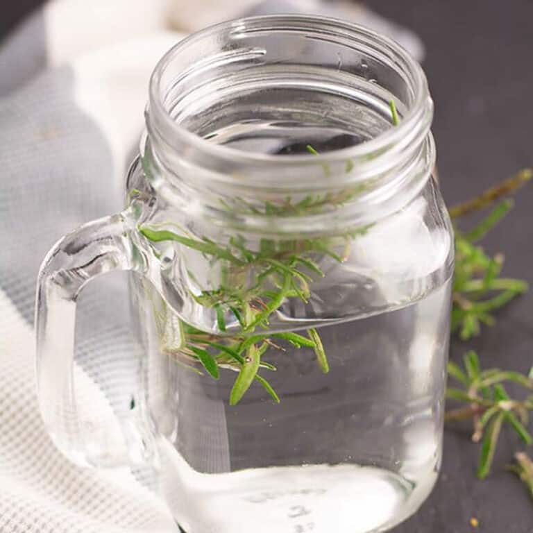rosemary tea served in a glass and garnished with fresh rosemary leaves