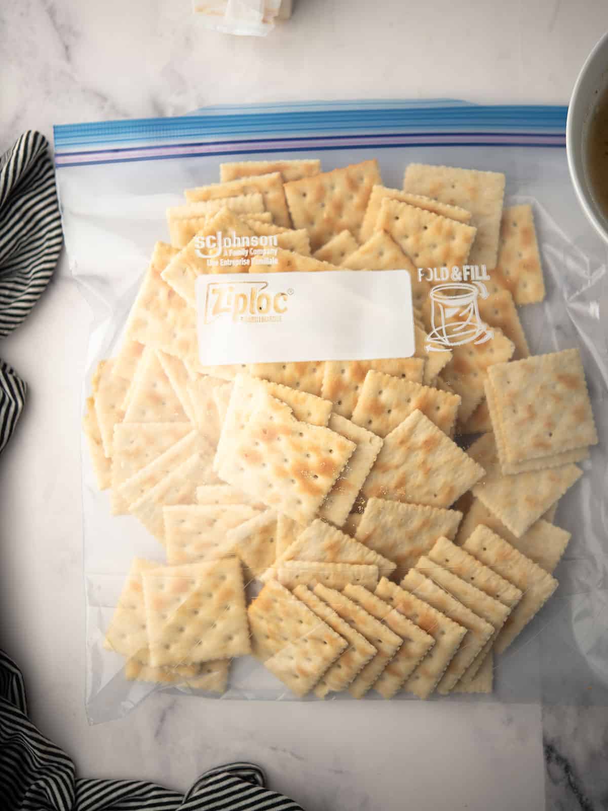 Saltine crackers being placed in a zip-top bag for coating.
