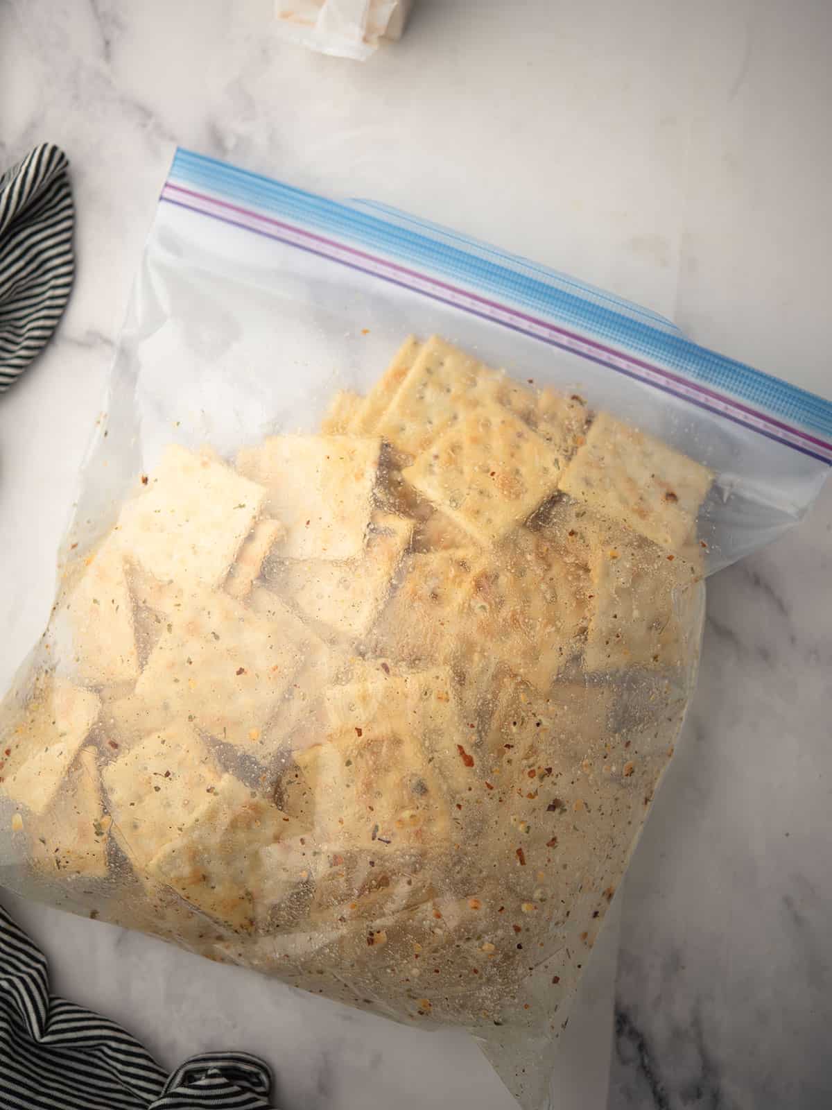 Flipping the bag to evenly coat the Saltine crackers with seasoning.