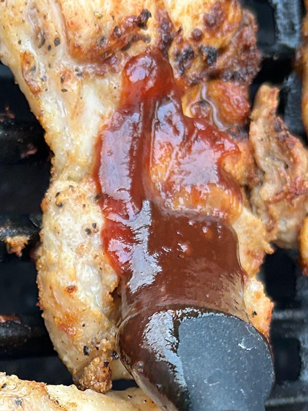 applying the bbq sauce over the chicken thighs