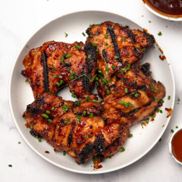 Baked BBQ Boneless Chicken Thighs are garnished and served in a plate.