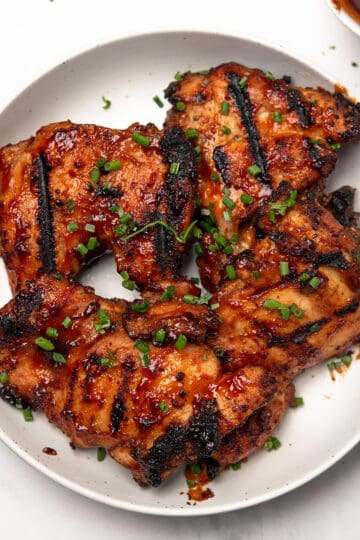 Baked BBQ Boneless Chicken Thighs are garnished and served in a plate.