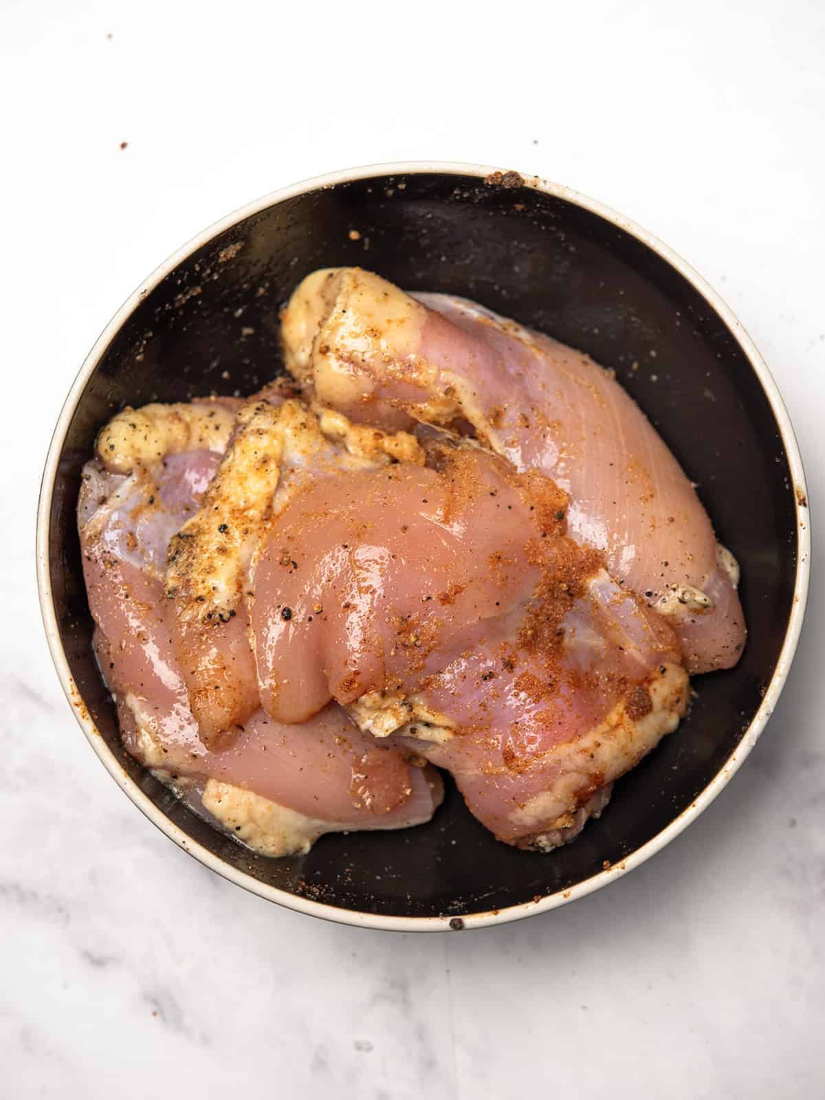 Seasoned boneless chicken thighs ready for baking