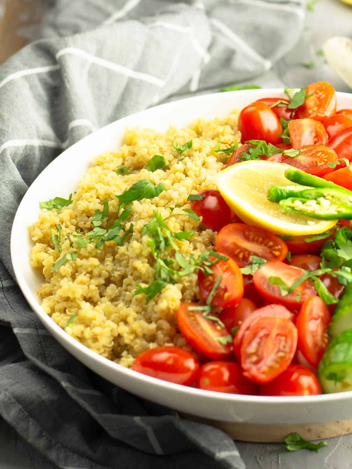 the fluffy cooked quinoa garnished with cilantro served in a white dinner bowl