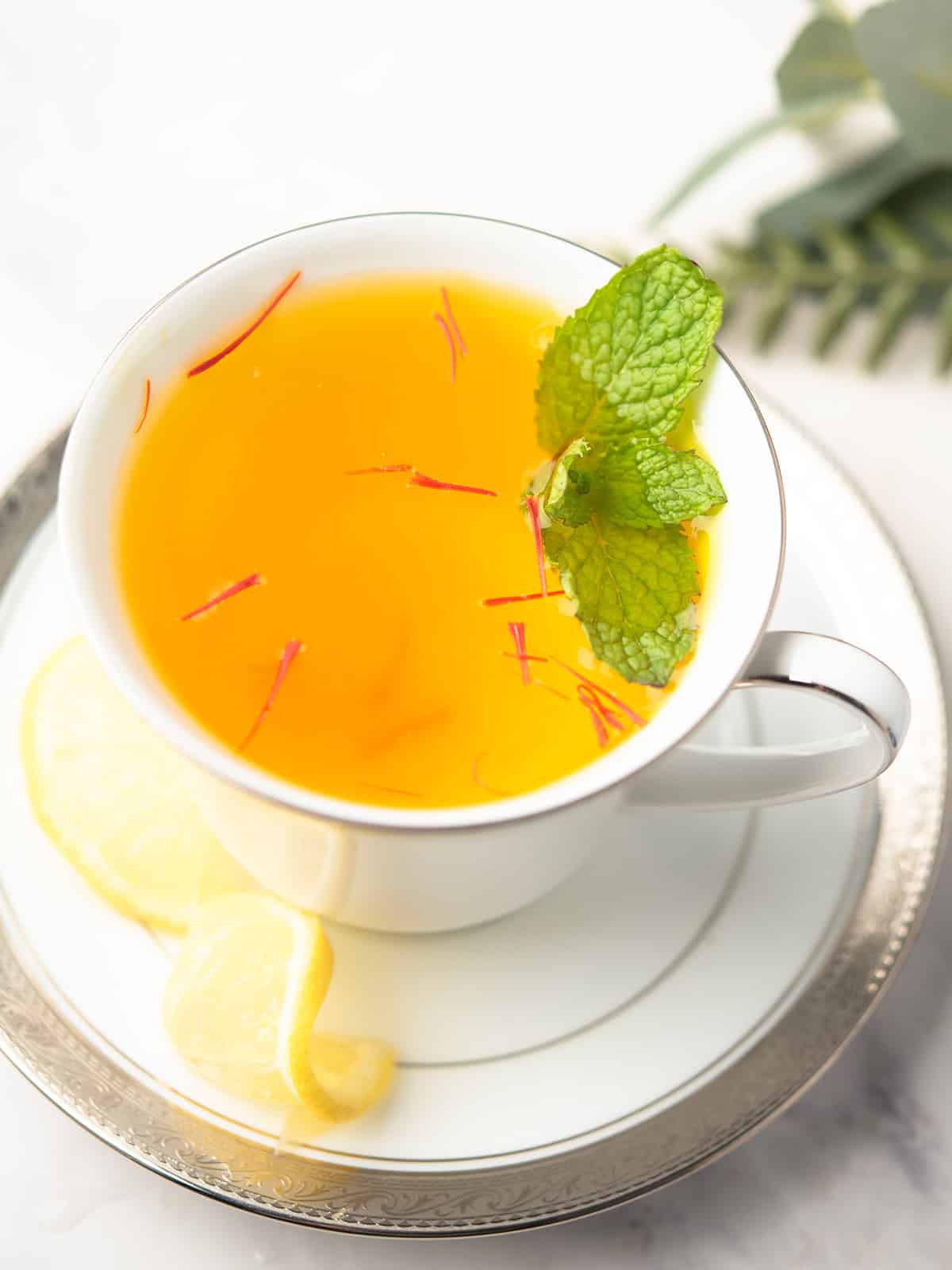 saffron tea served in a tea cups garnished with mint leaves