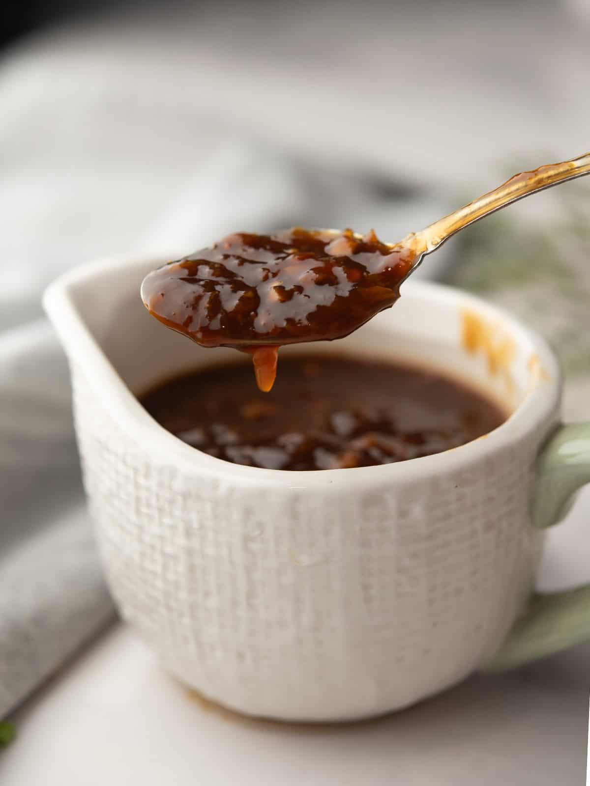 drizzling orange ginger sauce with a spoon and a bowl