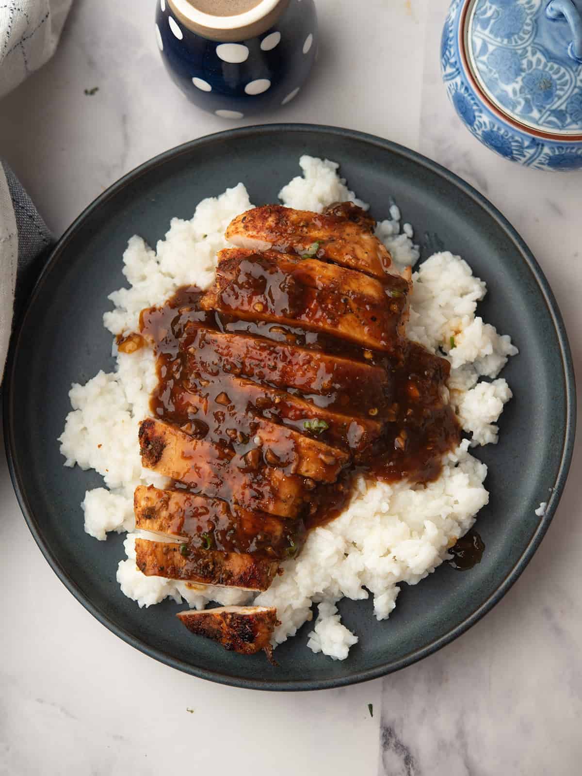 Close-up of orange ginger sauce drizzled over grilled chicken on a plate.