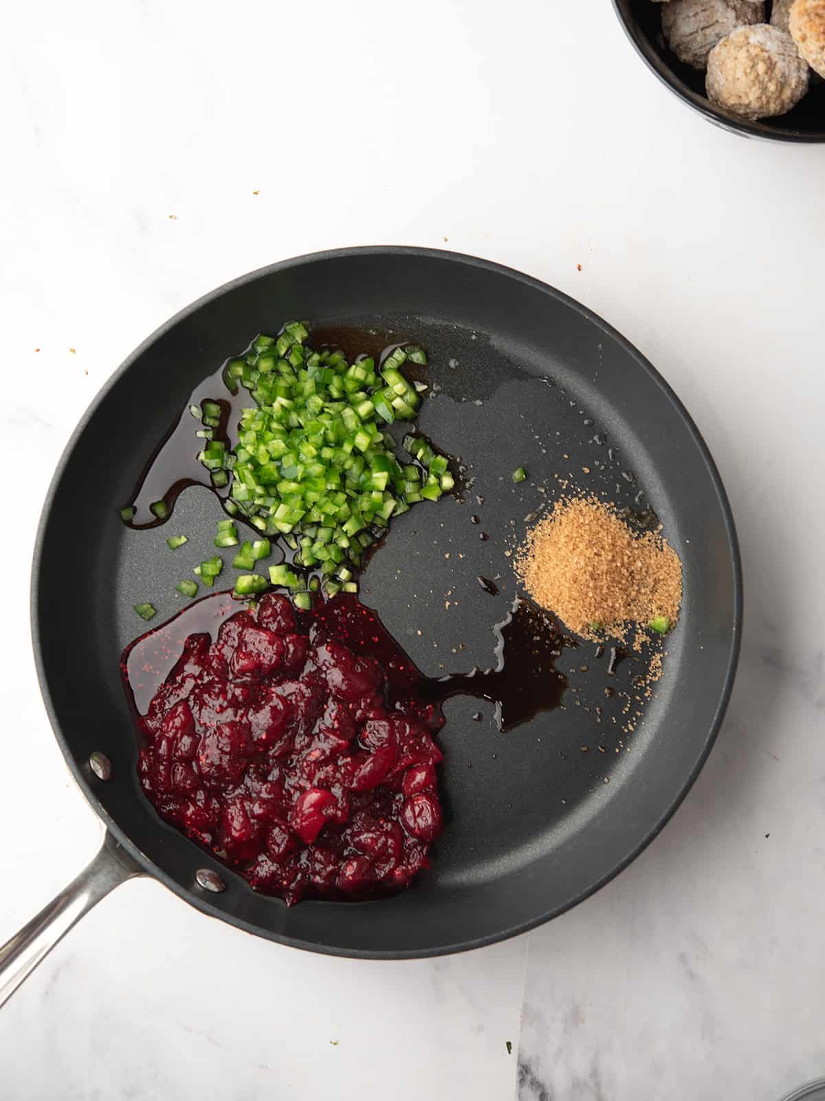 Cooking cranberry sauce with jalapeño in a skillet.