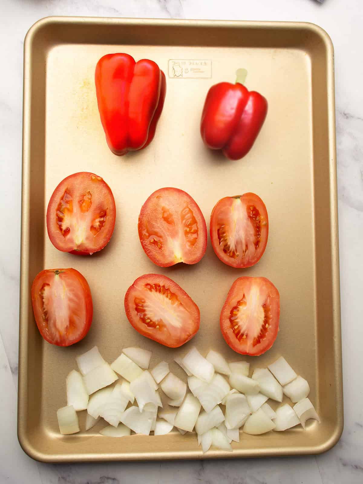 Vegetables on a baking sheet drizzled with olive oil, ready to roast in the oven