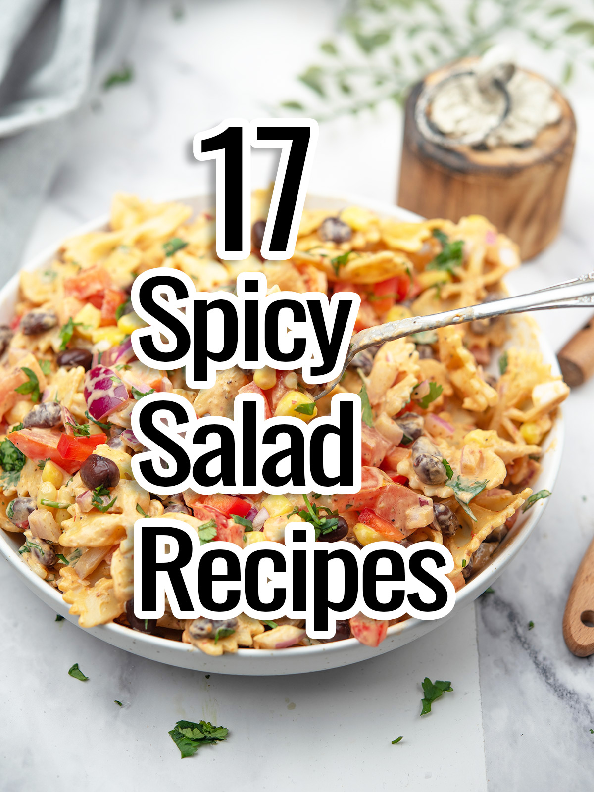 17 spicy salad recipes text showed with a pasta salad with a bowl and spoon