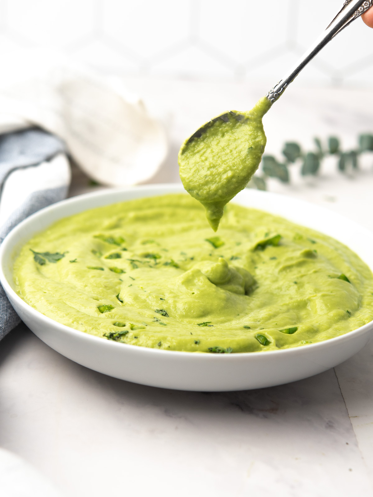 Smooth avocado sauce ready to serve with a spoon