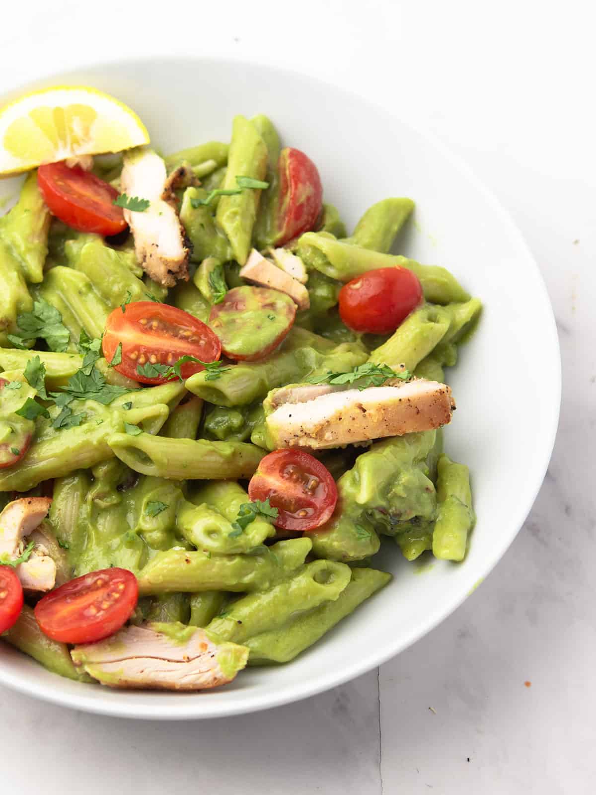 Close-up of avocado chicken pasta with fresh herbs